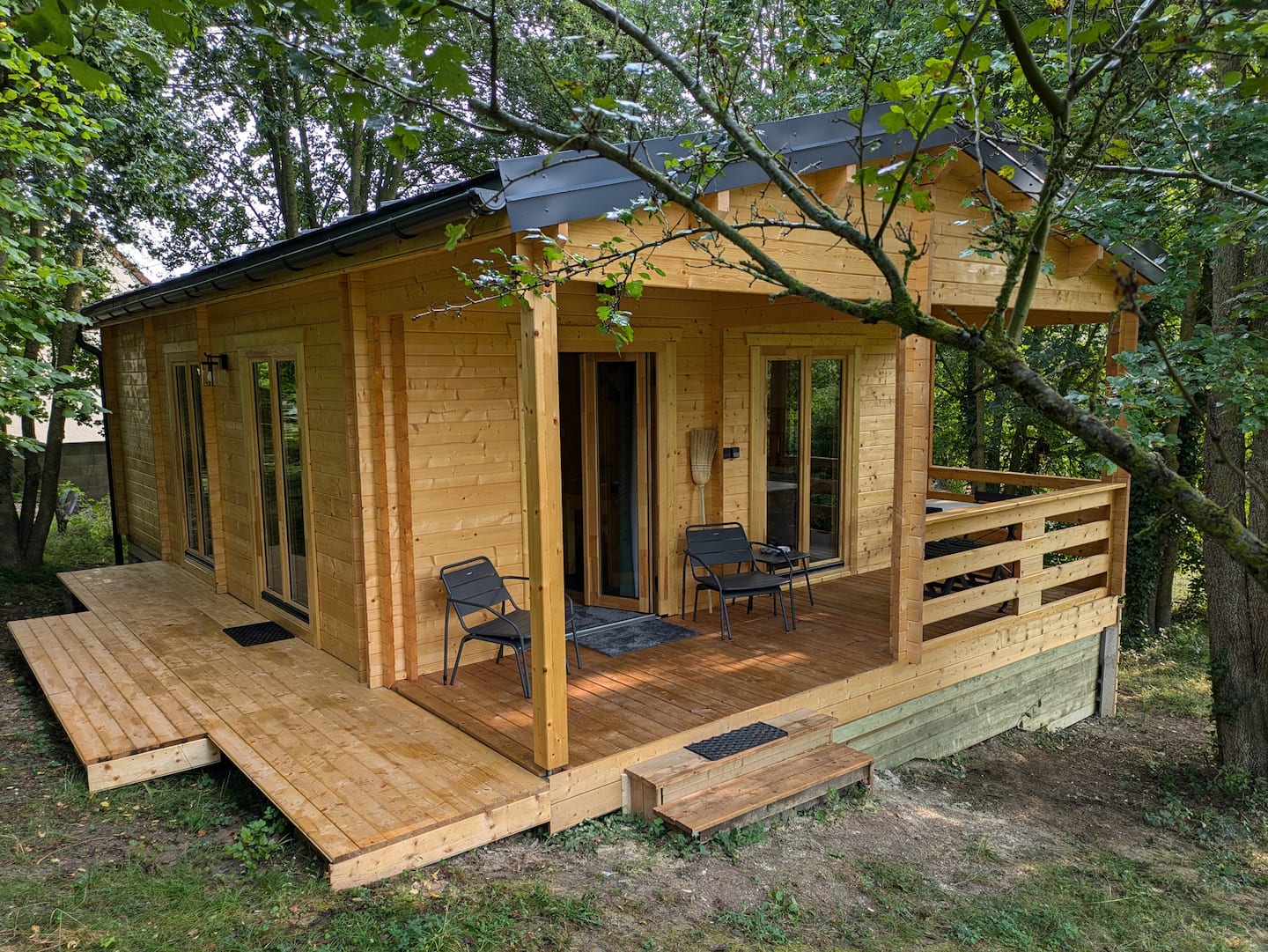 Le Chalet du Bois et sa terrasse couverte, entourés d’arbres